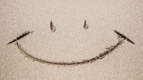 Ein Smiley ist am Strand im Sand gezeichnet. © fotolia.com Foto: adisa